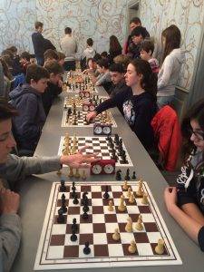 Schüler sitzen in einer Reihe an den Schachbrettern.